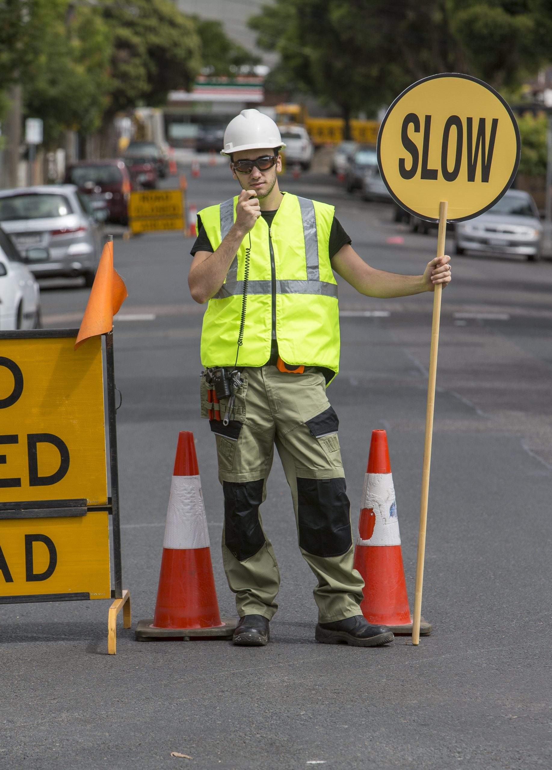 Traffic controller talking to radio and holding slow sign