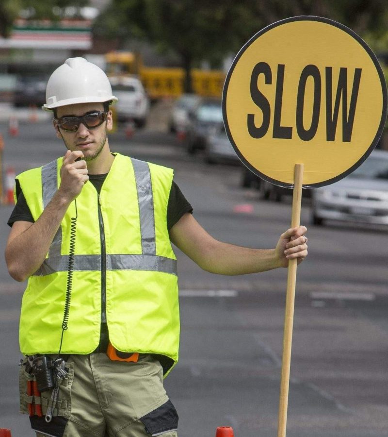 Traffic controller talking to radio and holding slow sign